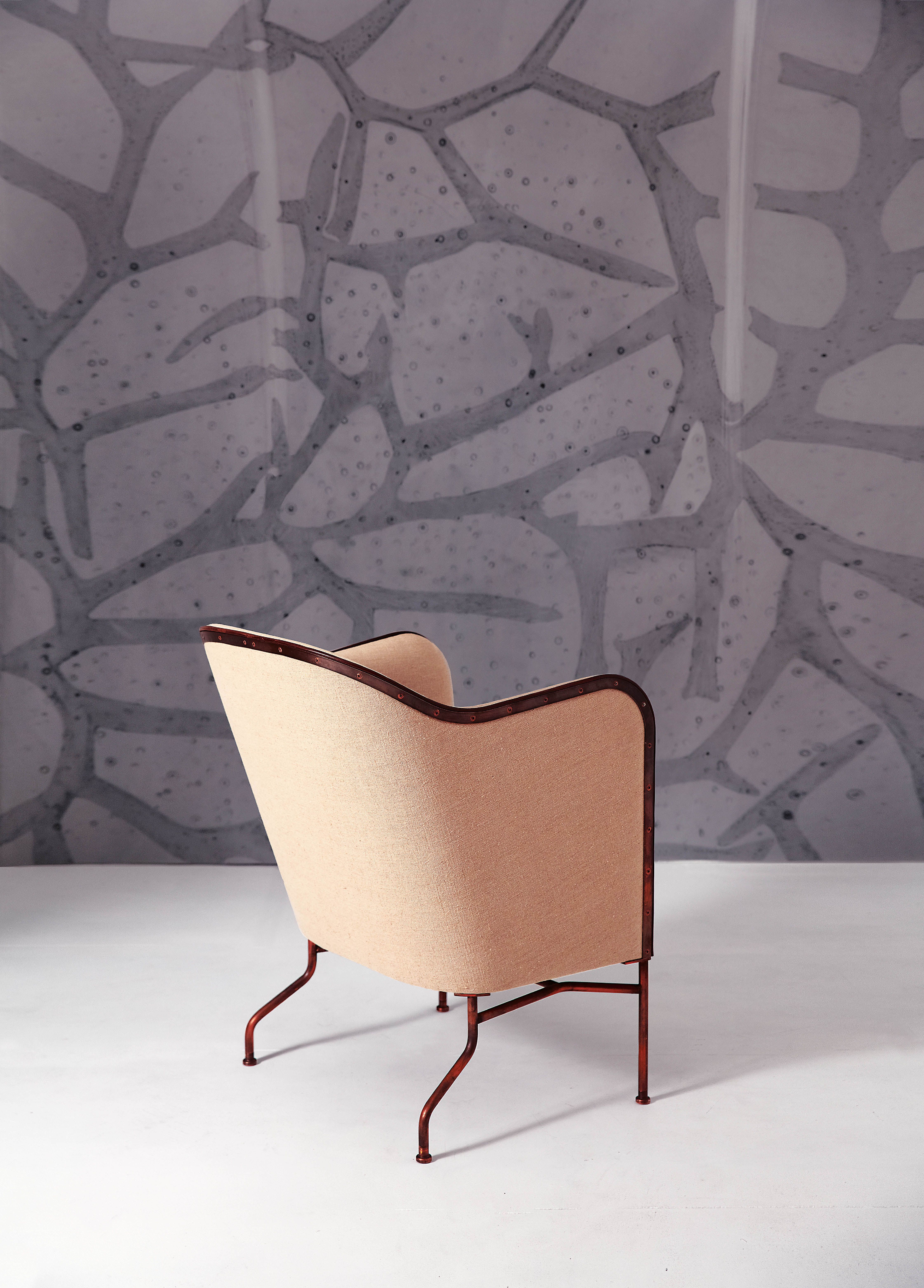 Star armchair in light fabric against a gray wallpapered wall.