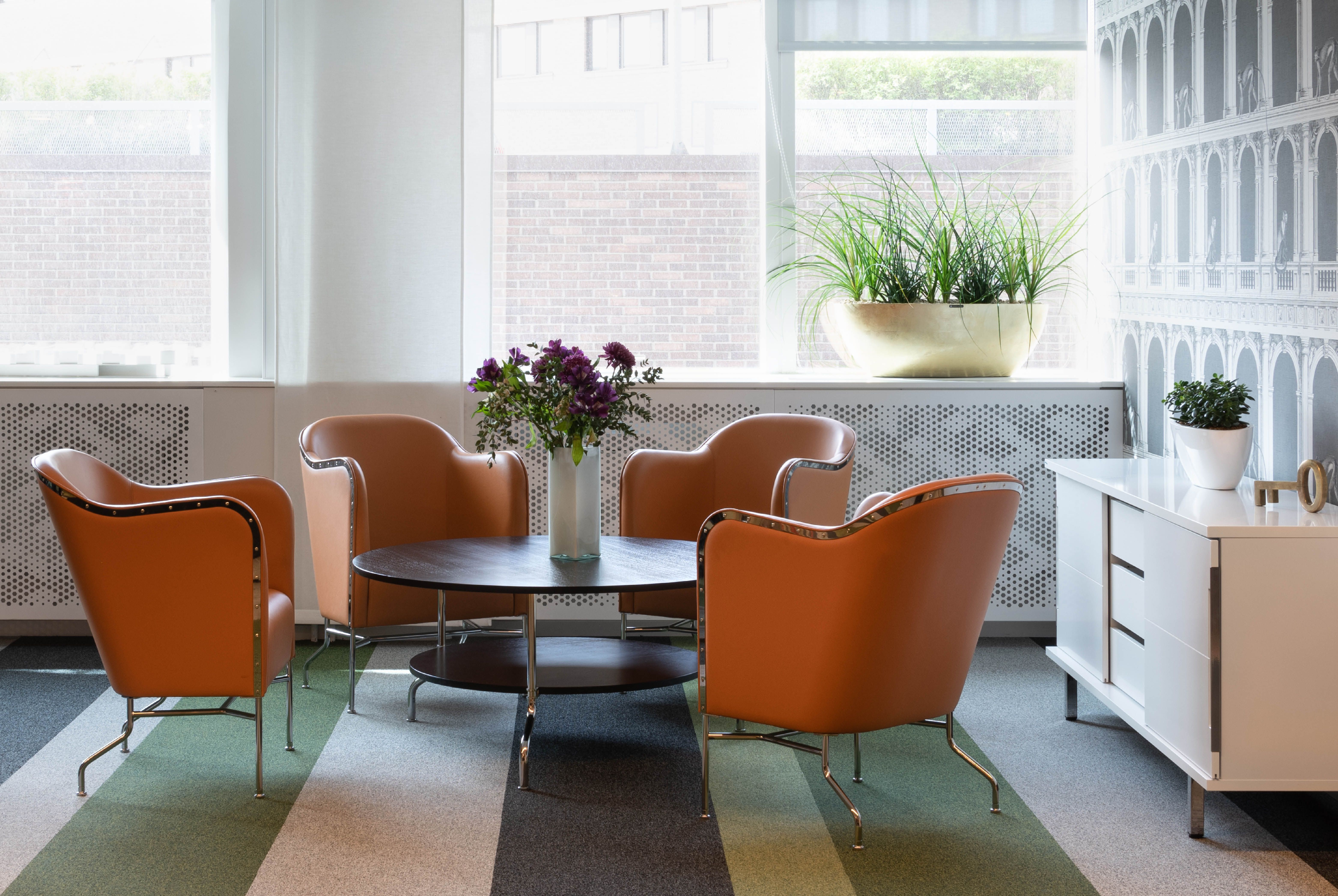 Two Star armchairs in front of a lush green plant wall.