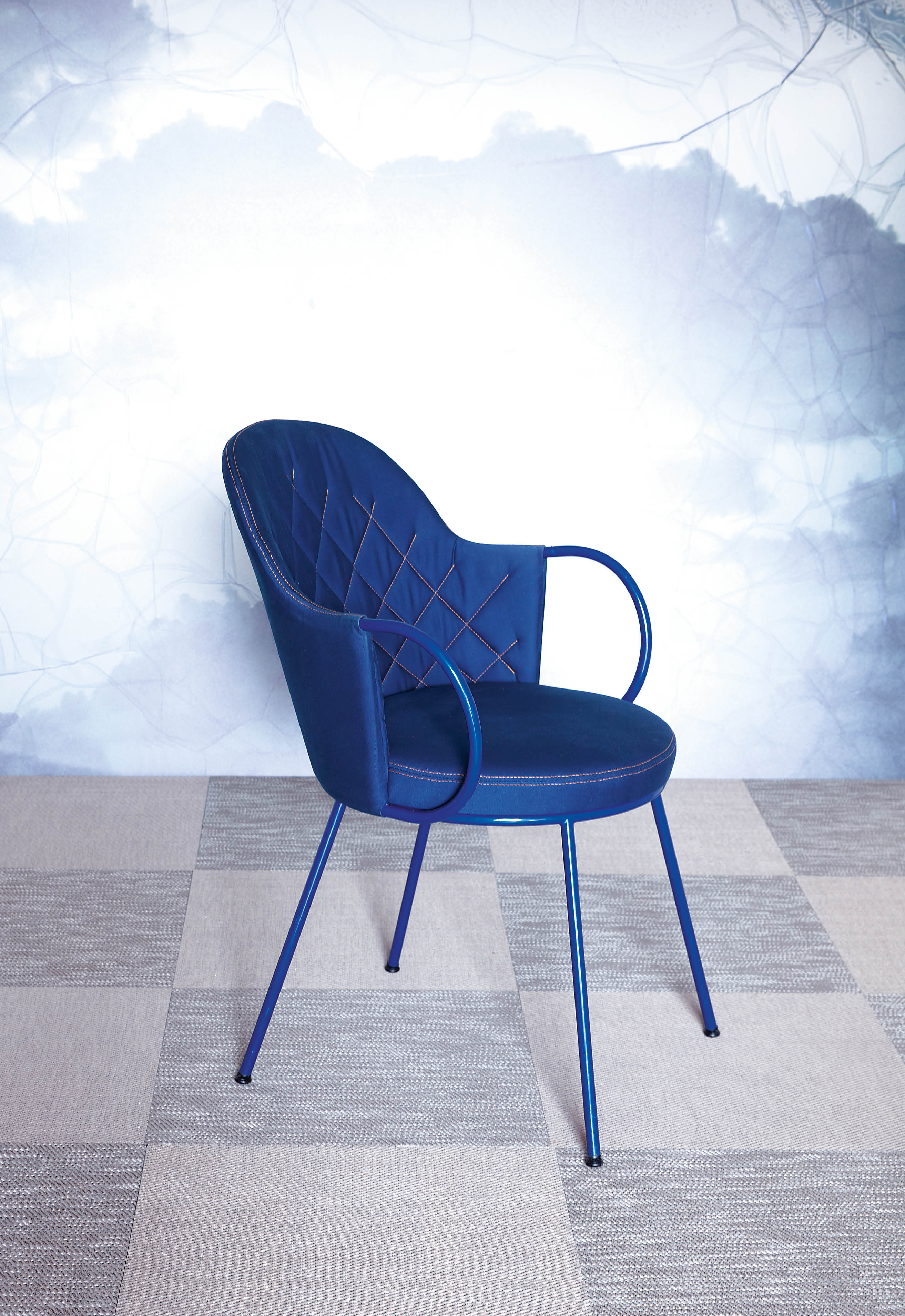 A blue Vienna chair standing in front of a wallpaper with clouds.